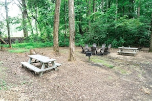 A forested campsite with picnic tables and Adirondack chairs. - Tiny Home Cottage Near the Smokies #4 Stella, Sevierville, Tennessee (Sevierville)