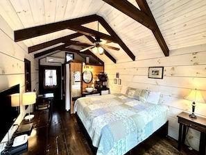 A cozy bedroom with a large bed, a ceiling fan, and wooden walls. - Tiny Home Cottage Near the Smokies #4 Stella, Sevierville, Tennessee (Sevierville)