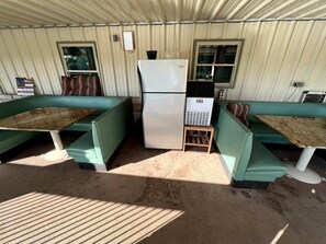 Un petit espace clos comprenant un réfrigérateur, une fenêtre et un banc.