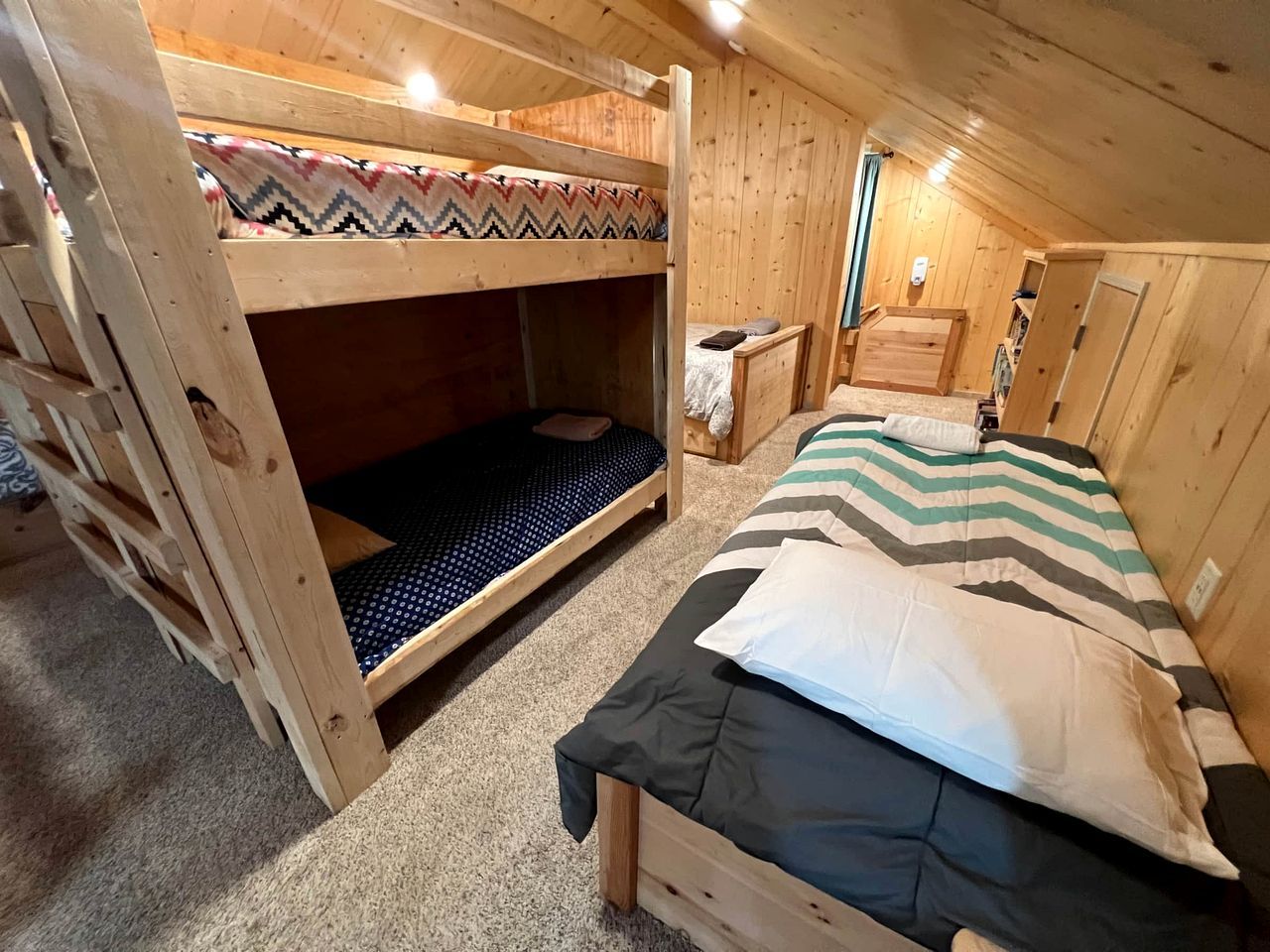 Una cabaña con literas, una cama individual, una mesita y una pared de madera.