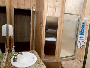 Une salle de bain en bois avec un lavabo, un porte-serviettes et un espace douche.