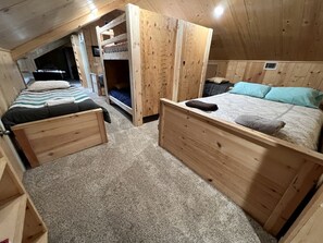 Une cabane en bois avec des lits superposés, un petit bureau et un sol recouvert de moquette.
