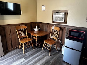 A small kitchenette with a microwave, a refrigerator, and a wooden table with chairs. - Rustic Cabin that Sleeps Three near Cedar Breaks National Monument, Cedar City, Utah (Cedar City)