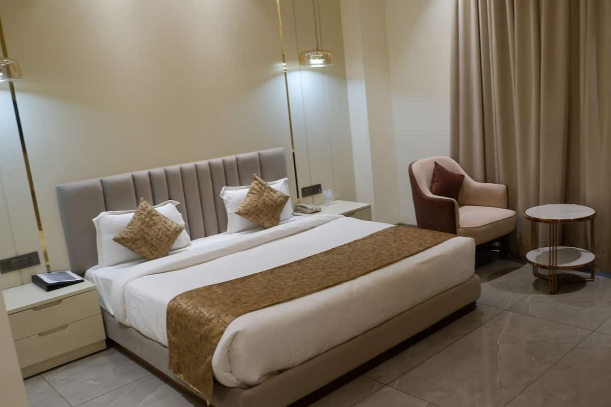 Una habitación de hotel con una cama grande, una silla, una mesita y un espejo.