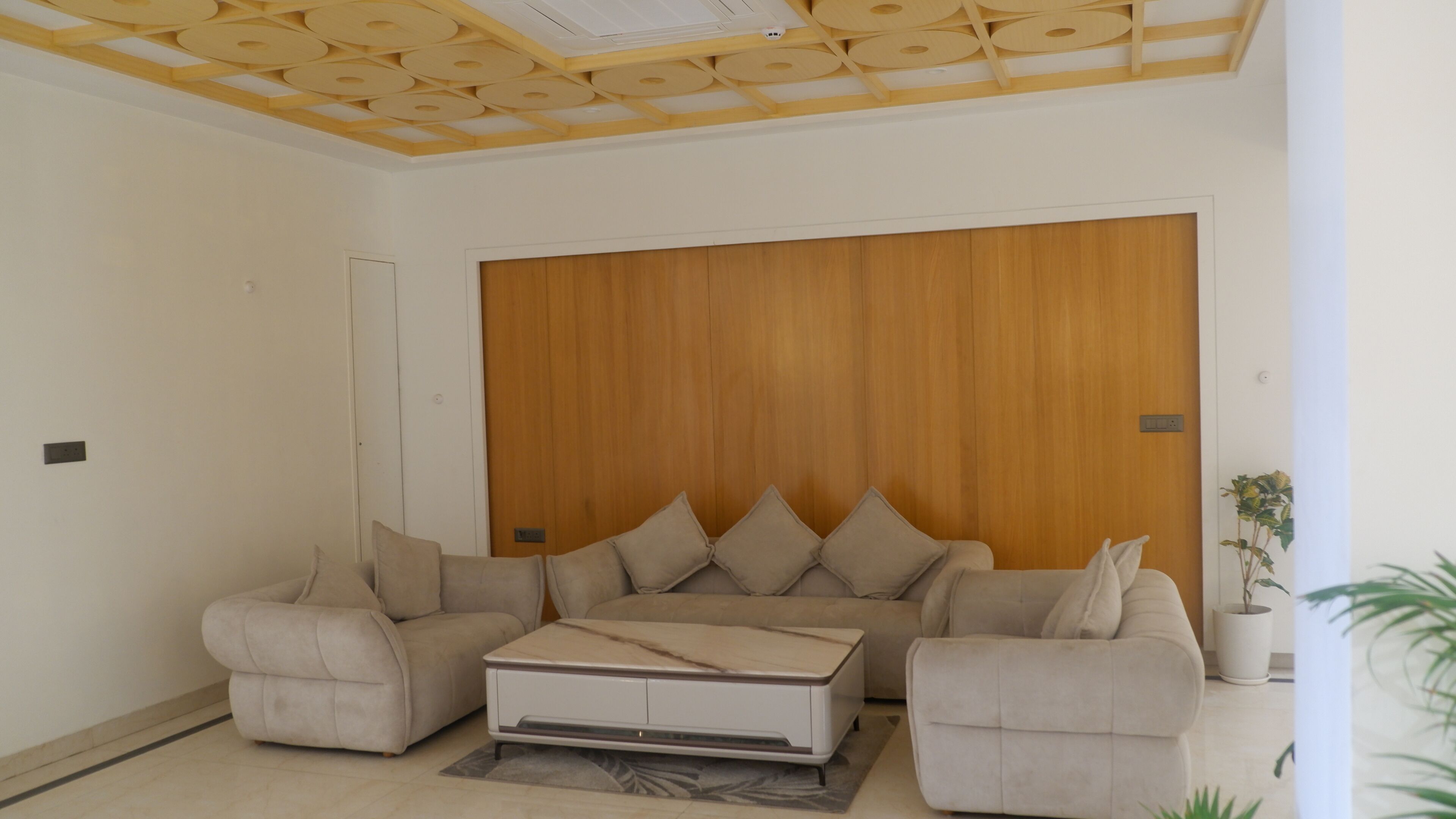 A living room with a sofa set, a coffee table, and a wooden accent wall.