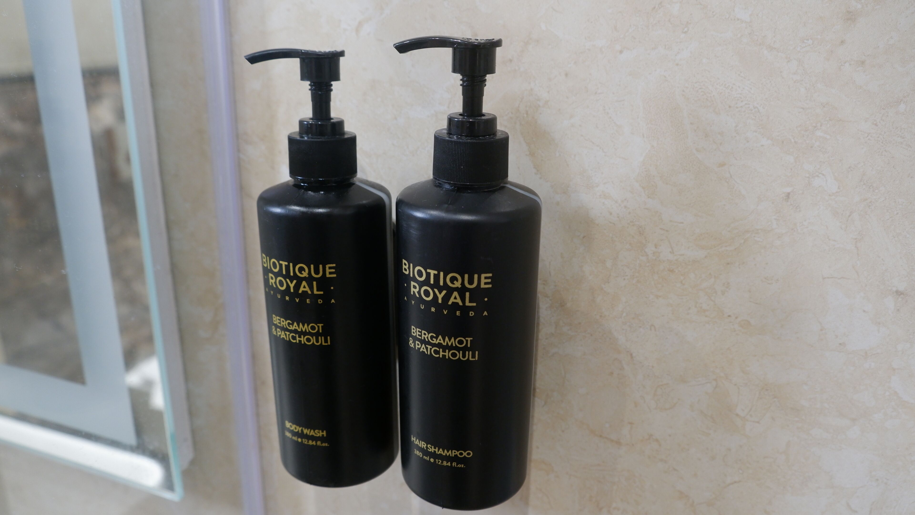 Deux flacons noirs de gel douche et de shampoing pour le corps de la marque Biotique Royal sont posés sur un mur.
