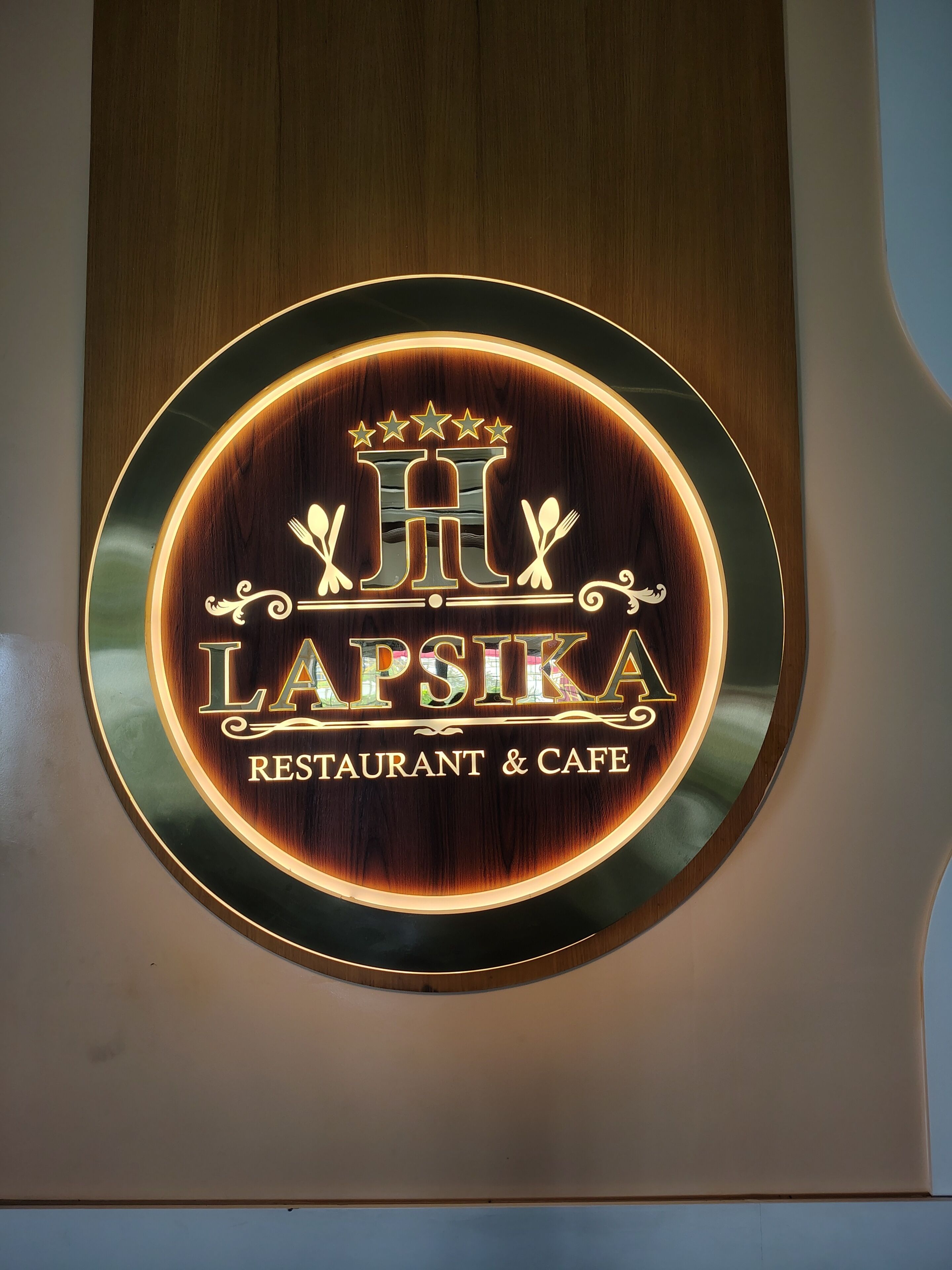 A circular sign with the name 'LAPSIKA RESTAURANT & CAFE' and decorative elements.