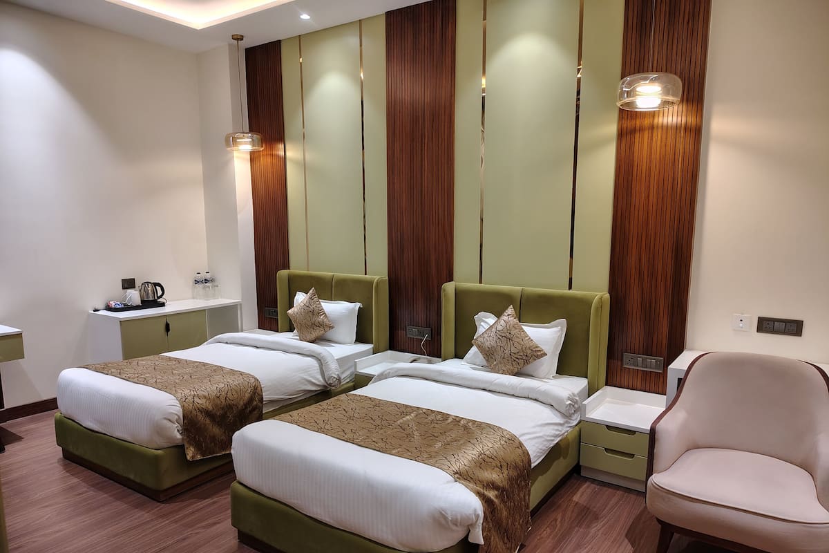 Una habitación de hotel con dos camas, una silla, una mesita pequeña y una mesita de noche.