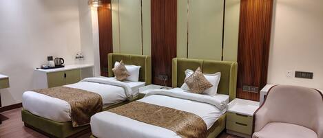 A hotel room with two beds, a chair, a small table, and a nightstand.