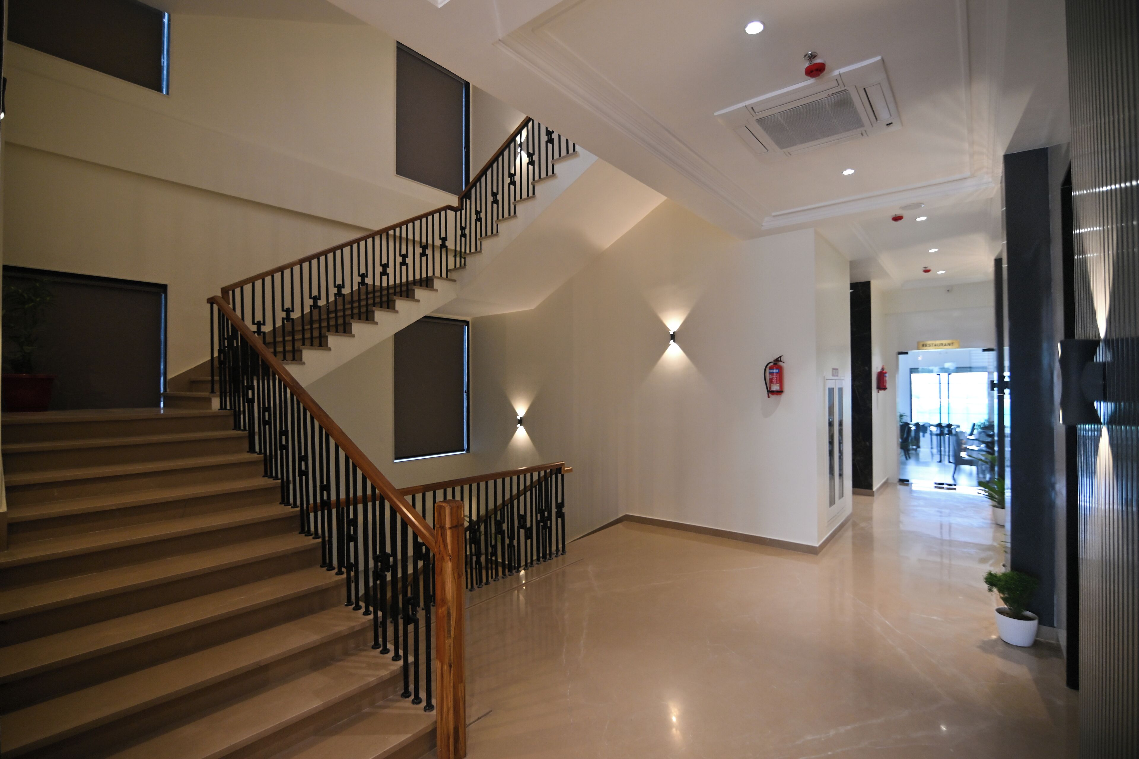 Un interior espacioso con una escalera de madera, un extintor y un diseño moderno.