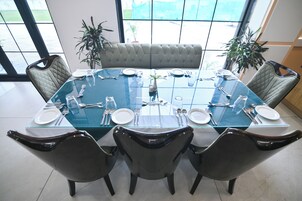 Una mesa de conferencias con cubierta de vidrio, rodeada por cuatro sillas y un banco acolchado en el centro.