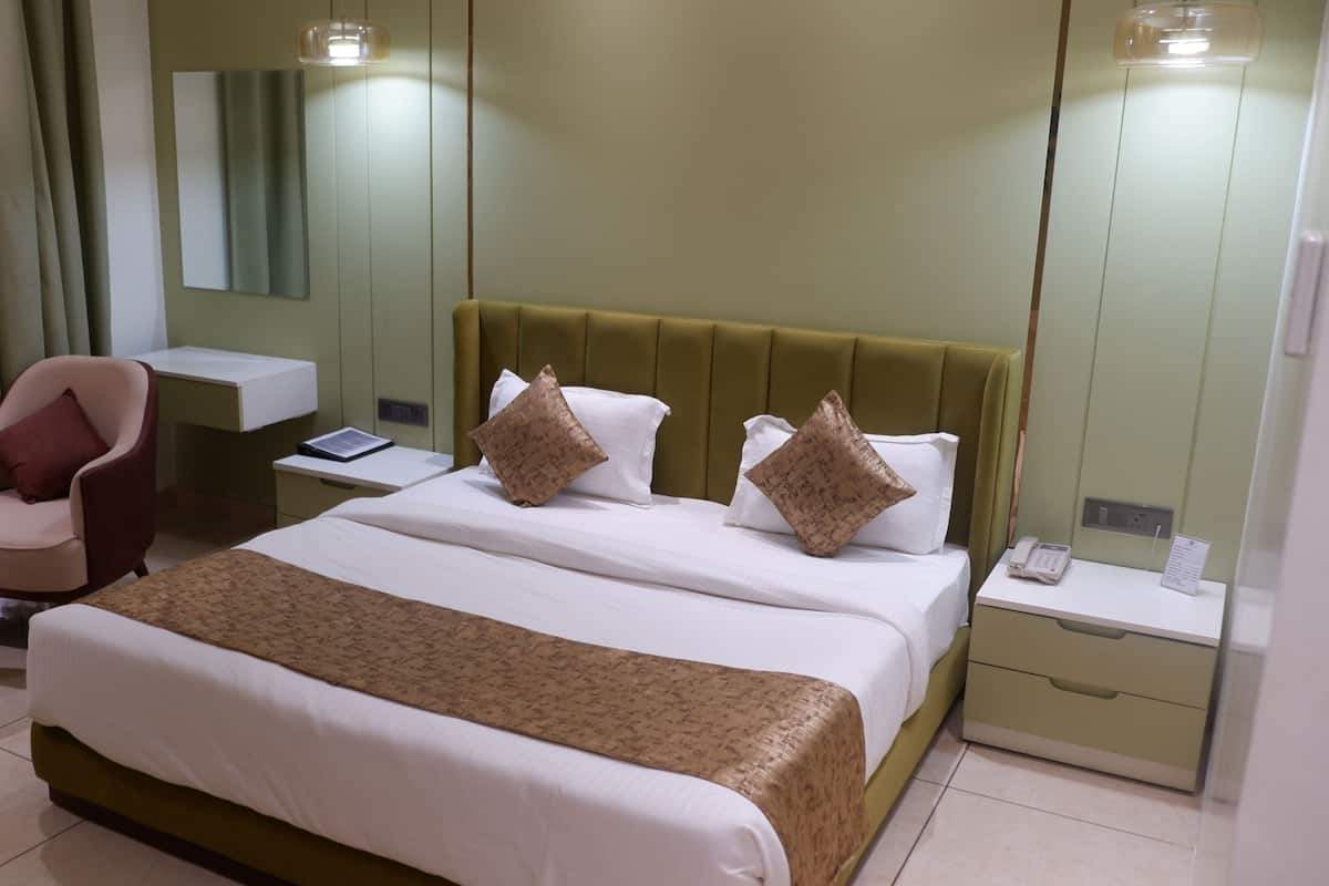 Una habitación de hotel con cama, escritorio, silla y mesita de noche.