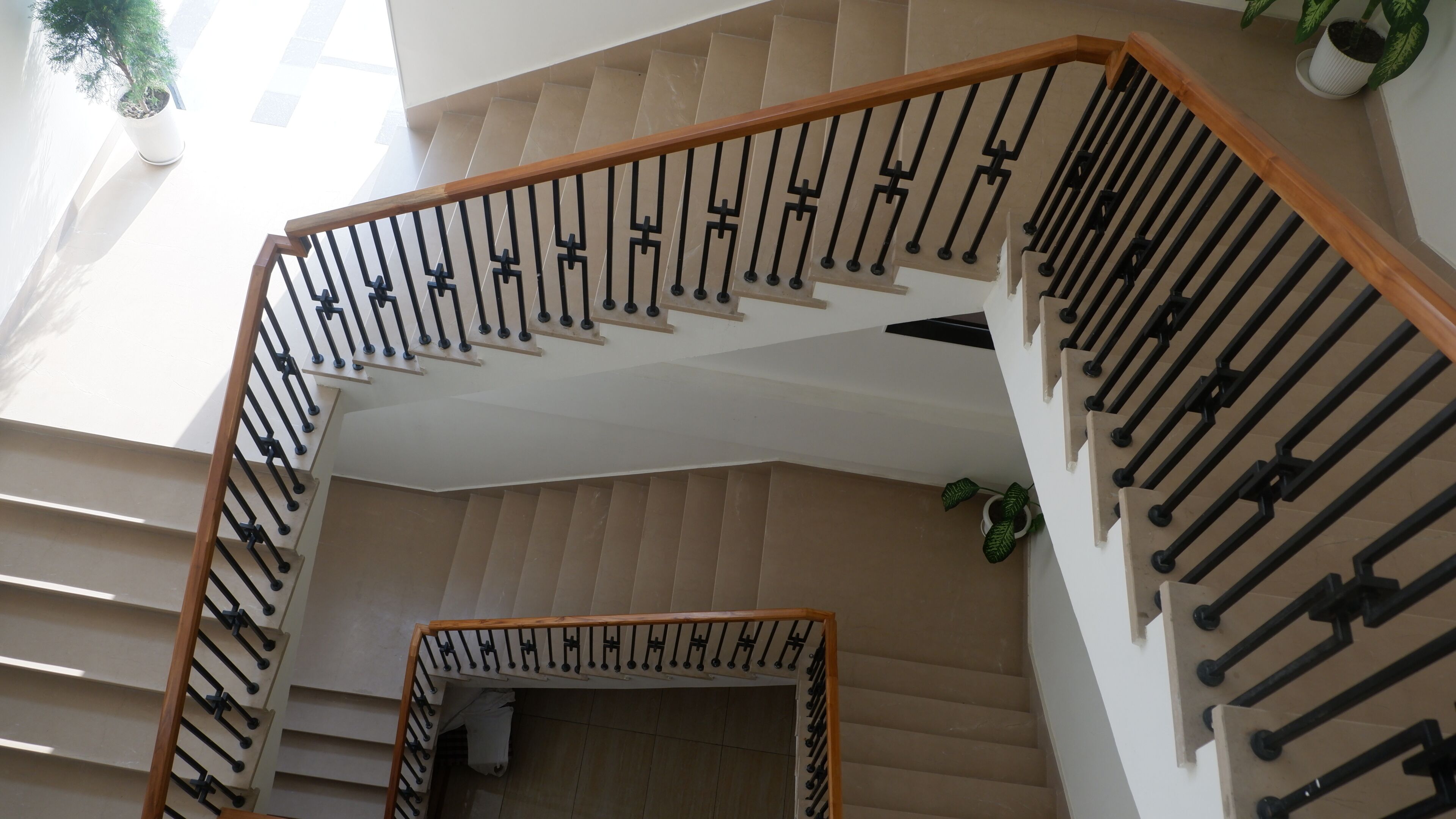 Una escalera con barandilla de madera y balaustres negros, que conduce a un piso superior.
