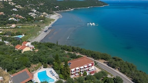 An aerial view of a coastal area with a swimming pool, a red-roofed building, and a beach. - Studio Apartment 'Apraos Bay Hotel  17' with Sea View, Wi-Fi and Air Conditioning (Απραος)