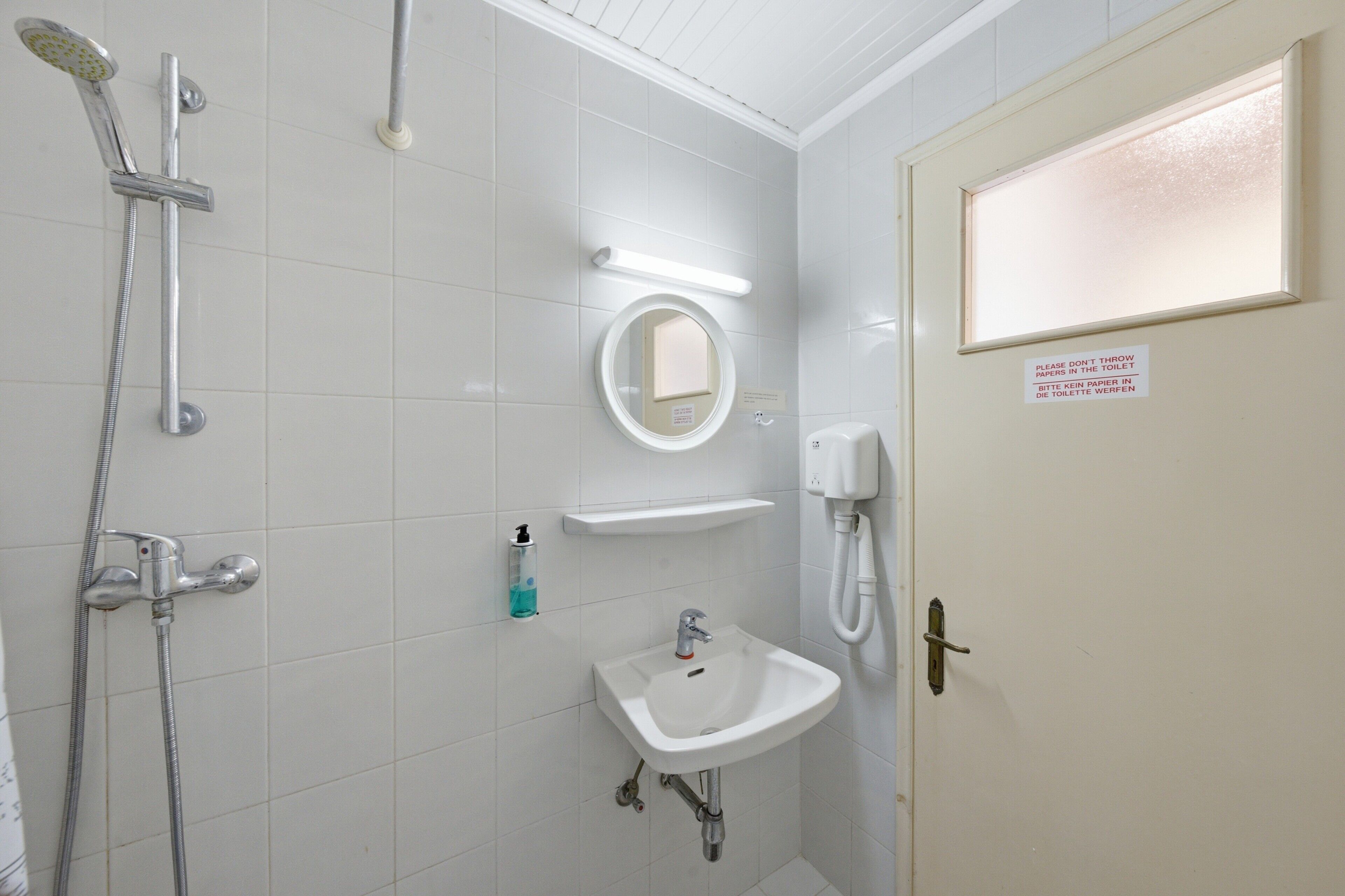 A bathroom with a shower, sink, mirror, and toilet.