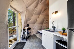 A compact kitchen with a sink, a coffee maker, and a small dining area.