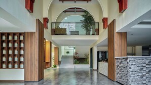 Un interior espacioso con una escalera central, estanterías de madera y una zona de cocina moderna.