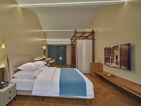Una habitación de hotel con cama, mesita de noche, lámpara y un cuadro grande en la pared.