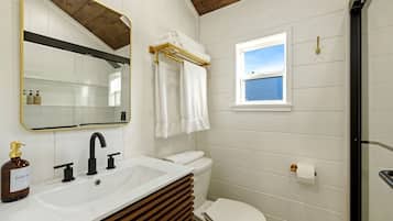 A bathroom with a white sink, a toilet, a mirror, and a window.