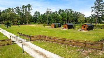 A fenced property with multiple cabins, a gravel path, and a grassy area.