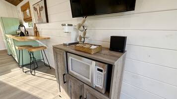 A kitchen with a microwave, a coffee maker, and a TV mounted on the wall.