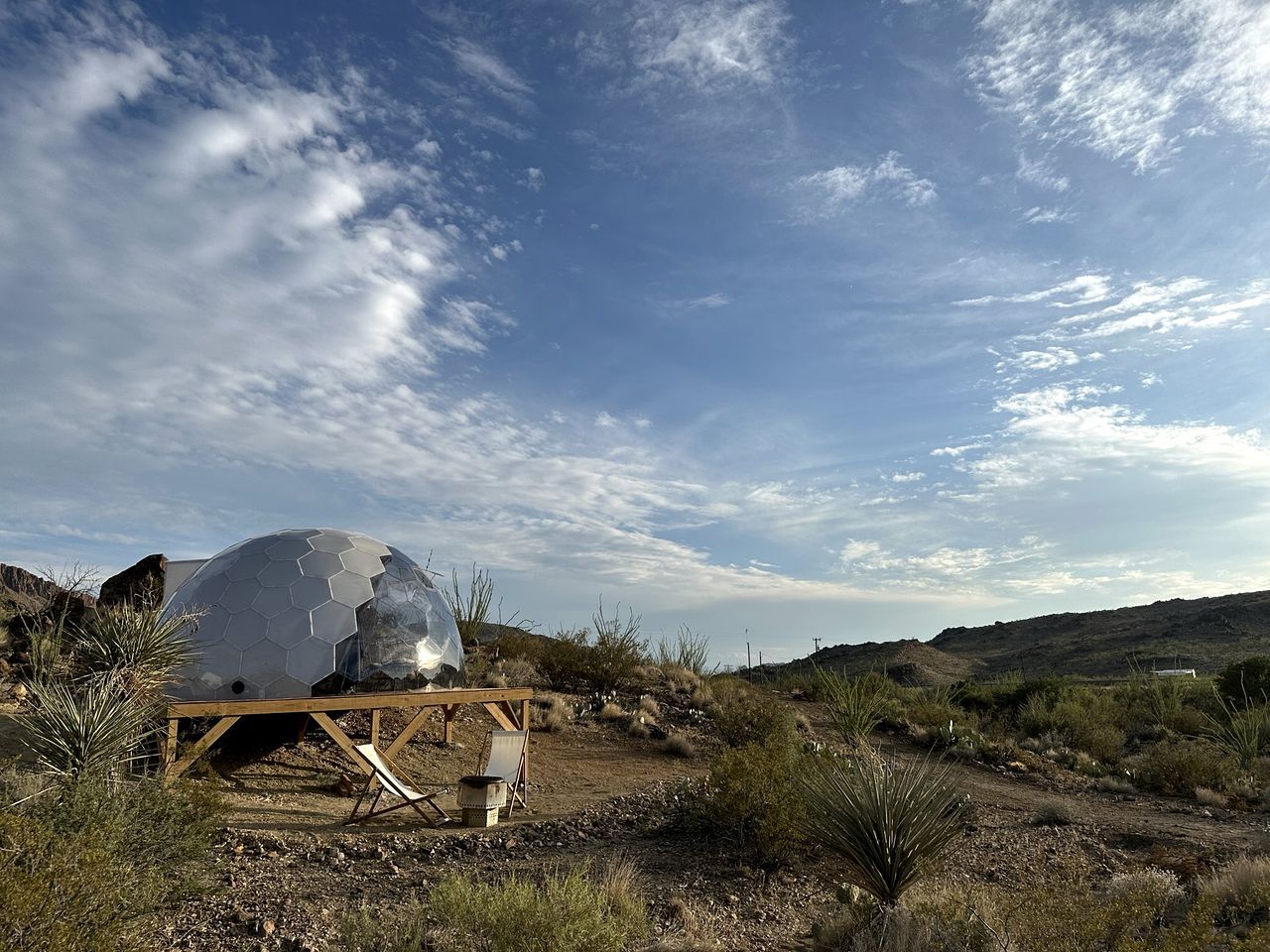 A large geodesic dome structure in a natural landscape with sparse vegetation.