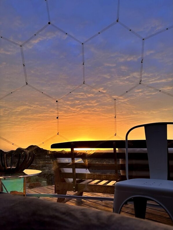 A hexagonal ceiling structure, a wooden deck, and a chair.