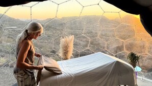 Una stanza con un letto, una finestra con motivo esagonale e vista su un paesaggio montuoso.
