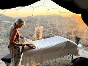 A room with a bed, a window with a hexagonal pattern, and a view of a mountainous landscape.
