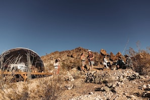 A dome-shaped structure with a wooden deck in a desert landscape.