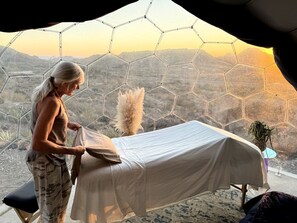 A room with a bed, a window with a hexagonal pattern, and a view of a mountainous landscape.