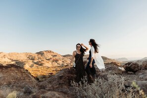Two people on rocky terrain with a mountainous backdrop.