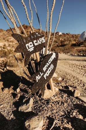 A desert landscape with a signpost indicating 'NO CARS' and 'ALL SPACE PODS.'