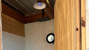 Un piccolo box doccia con porta in legno, una ventola a soffitto e un riscaldatore a parete.