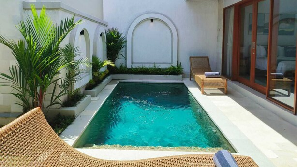 Un'area piscina privata con un piccolo giardino, un pontile in legno e una stanza con pareti in vetro.