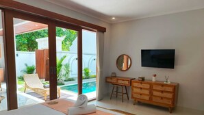 Camera d'albergo con un letto, una TV, una scrivania e vista su una piscina.