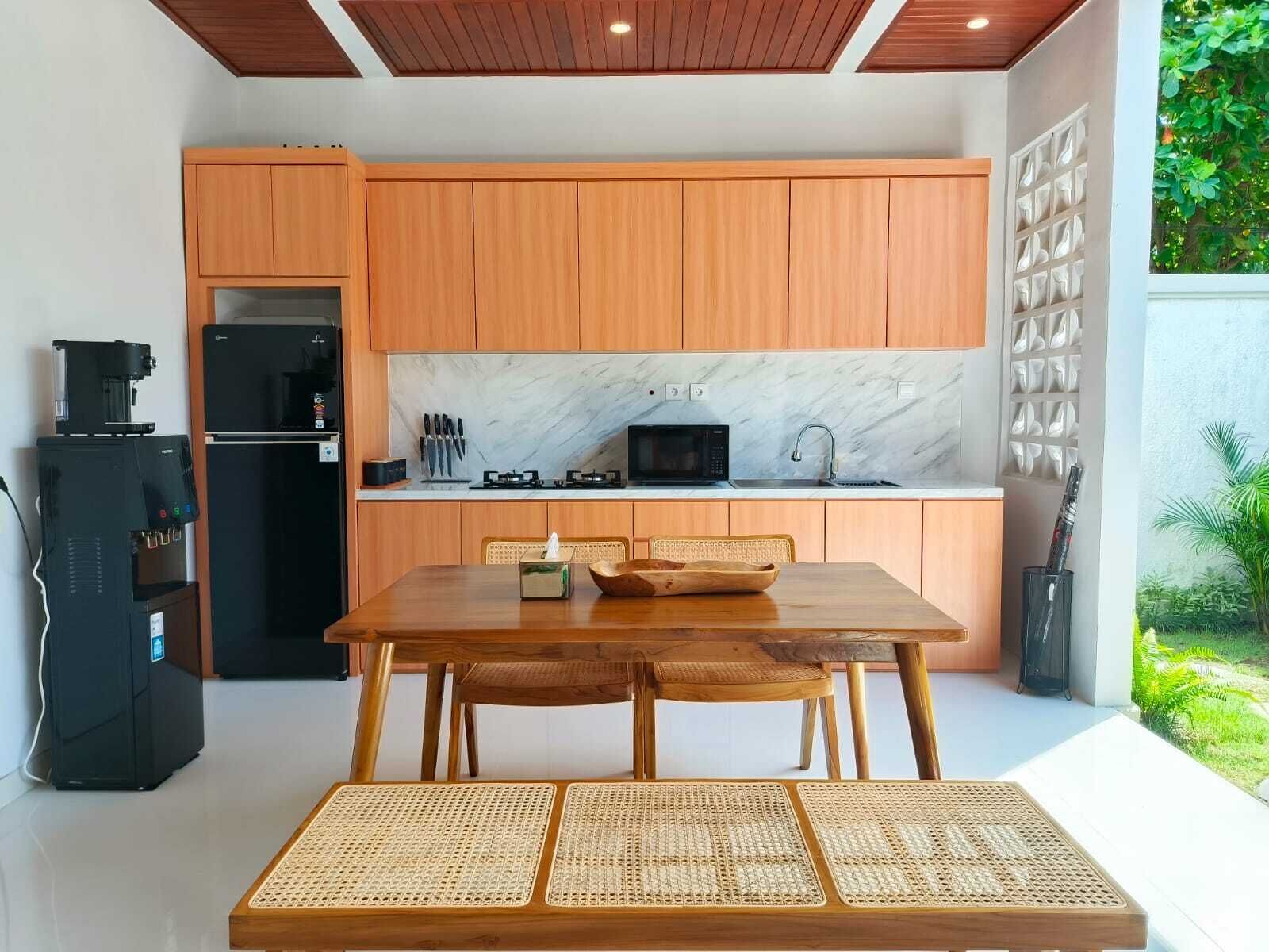 Een moderne keuken met houten kastjes, een marmeren spatwand en een eethoek met een houten tafel en geweven stoelen.