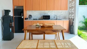Una cucina moderna con mobili in legno, uno schienale in marmo e un'area pranzo con tavolo in legno e sedie in vimini.