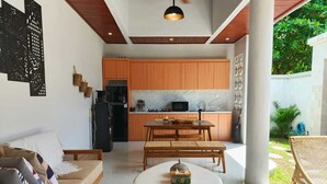Una cucina moderna con mobili in legno, un piano di lavoro in marmo e un'area pranzo con un tavolo rotondo e sedie in vimini.