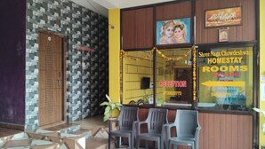 A hotel reception area with a reception desk, a sign for rooms, and a poster of a deity. - Naga Chowdeshwari Homestay (Kumta)