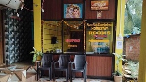 A reception area with a reception desk, chairs, and a patterned floor. - Naga Chowdeshwari Homestay (Kumta)