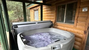 A hot tub in a wooden cabin with a window and a door.