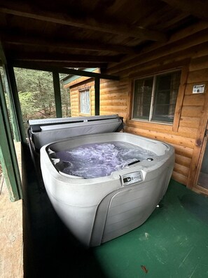 A hot tub in a wooden cabin with a window and a door.