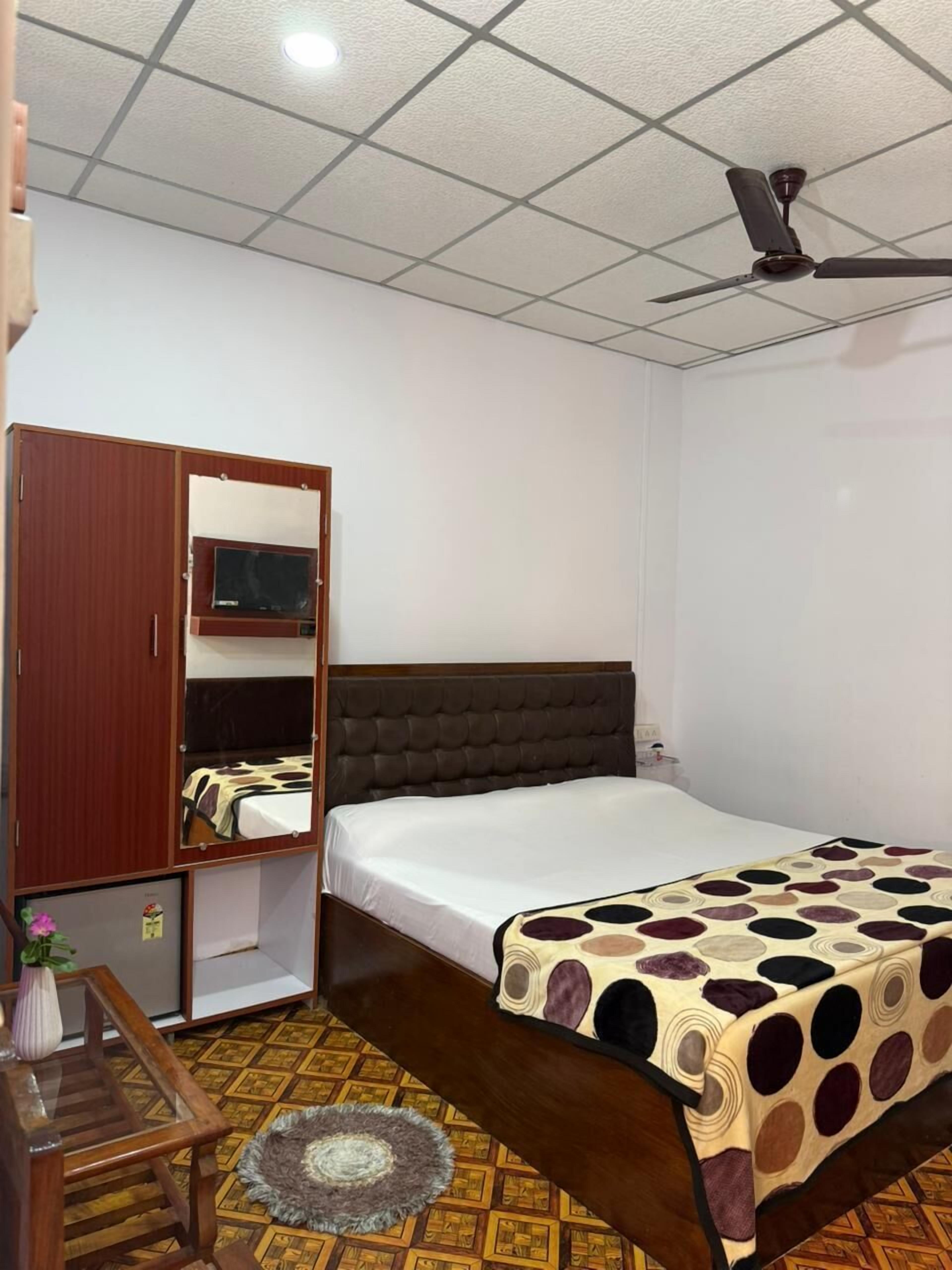 A bedroom with a bed, a wardrobe, a ceiling fan, and a patterned rug.