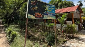 Un cartel anuncia opciones de comida vegetariana y no vegetariana, con un número de contacto y una dirección.