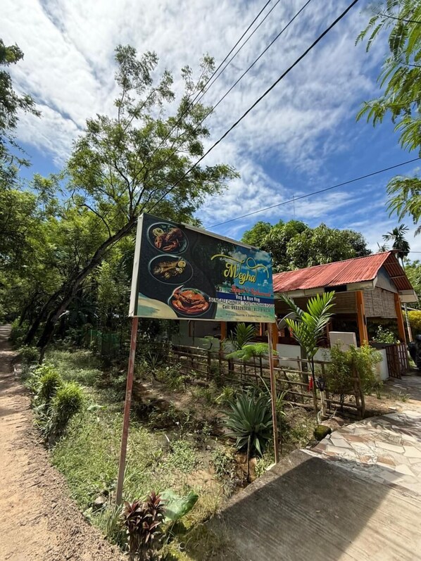 A signboard advertising vegetarian and non-vegetarian food options, with a contact number and address. - Megha Resort And Restaurant (Port Blair)
