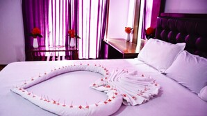 Una cama bien hecha con una toalla doblada en forma de corazón, una almohada blanca y un cabecero.