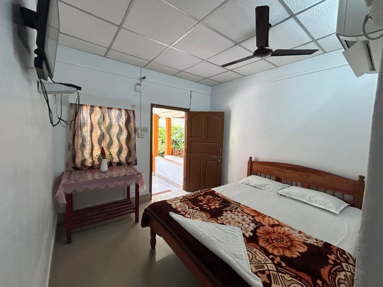 A bedroom with a bed, a desk, and a ceiling fan.