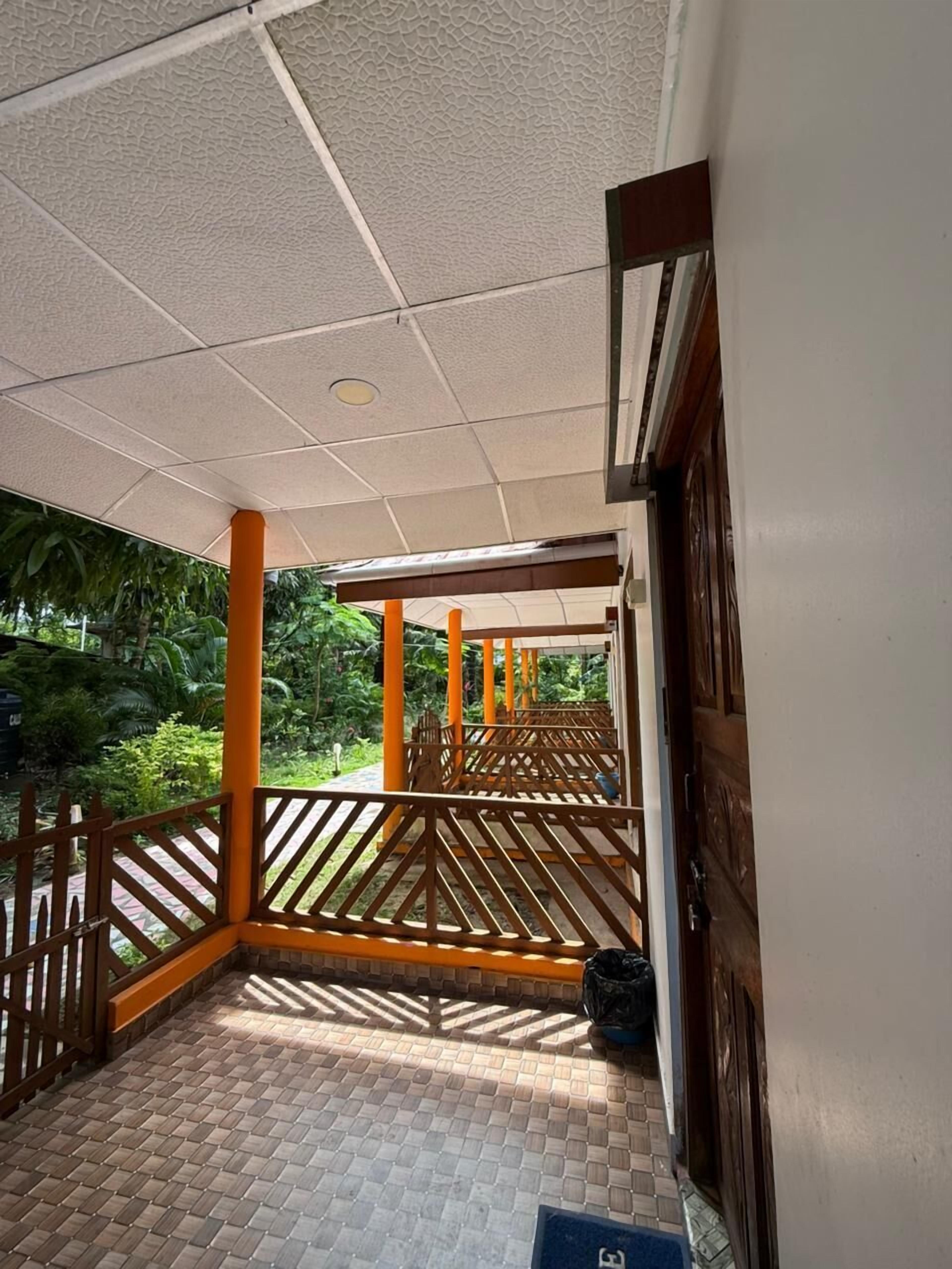 Un espacio al aire libre cubierto con piso de baldosas, barandillas de madera y una puerta a la derecha.