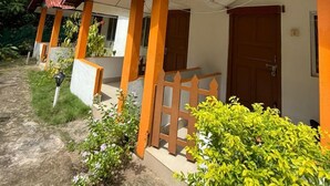Filas de alojamientos tipo bungalow con techos rojos y paredes blancas, rodeados de exuberante follaje y palmeras.